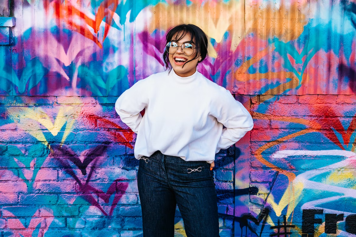 A smiling woman standing in front of a colorful wall